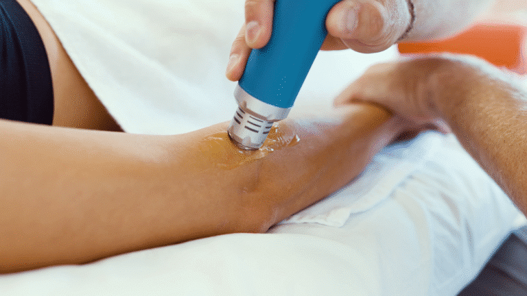 A chiropractor applies shockwave therapy to a patient’s elbow using a handheld device to reduce pain and inflammation.