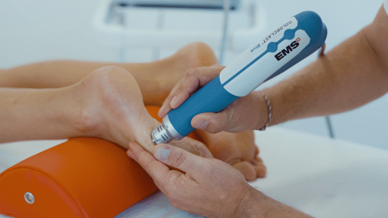 A chiropractor performs shockwave therapy on the sole of the foot to treat plantar fasciitis.