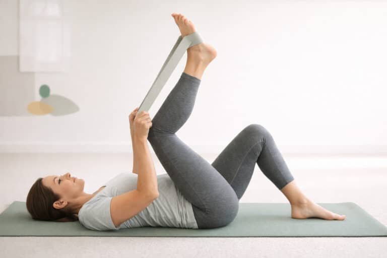Patient performing a hamstring stretch on a yoga mat as part of chiropractic rehabilitation and lower back pain treatment in Brooklyn, NY