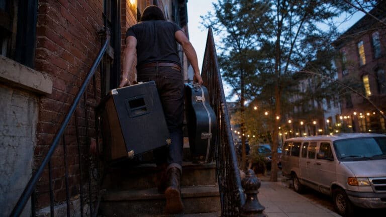 Musician hauling amp gear up stairs, illustrating musician back pain in Brooklyn treated at Brooklyn Chiropractic Care in Greenpoint