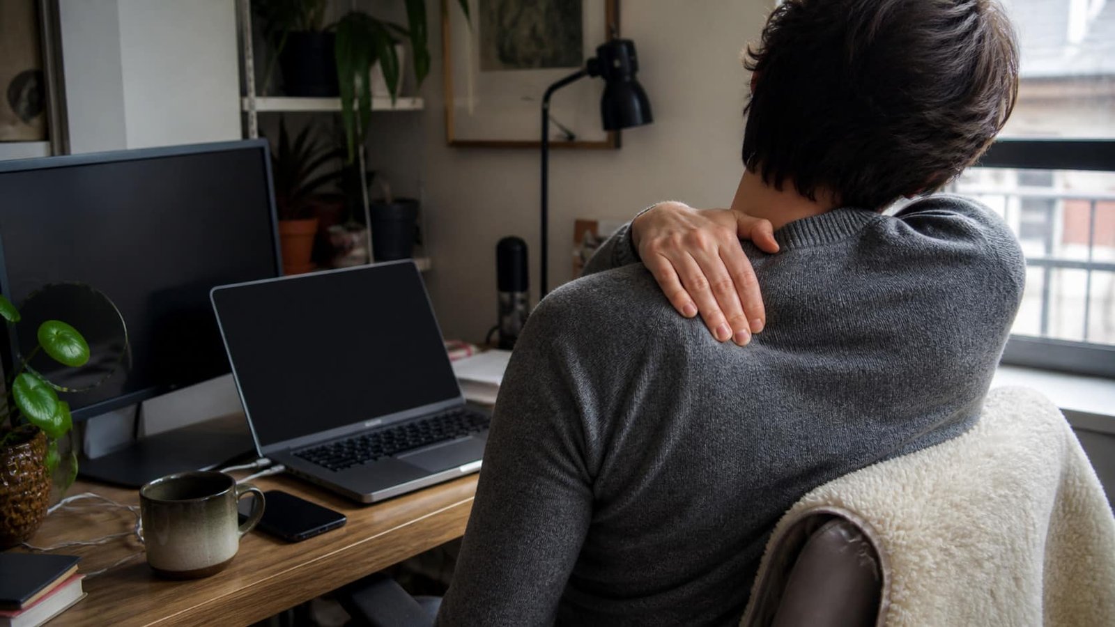 Person with trapezius pain and neck stiffness at a desk, treated at Brooklyn Chiropractic Care in Greenpoint